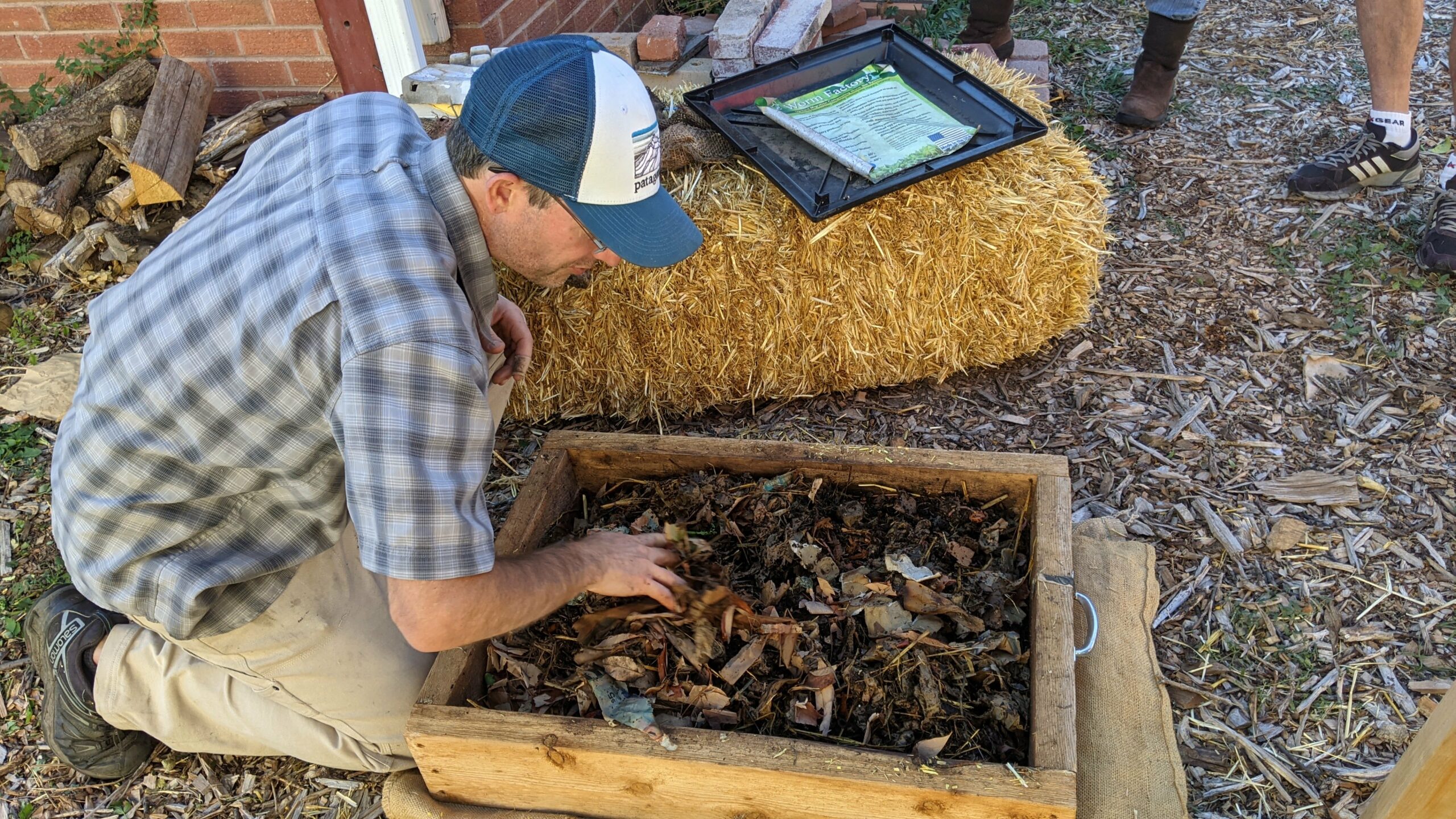 Person crouching next to a compost sifting box